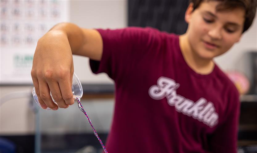 A boy pours water down a string